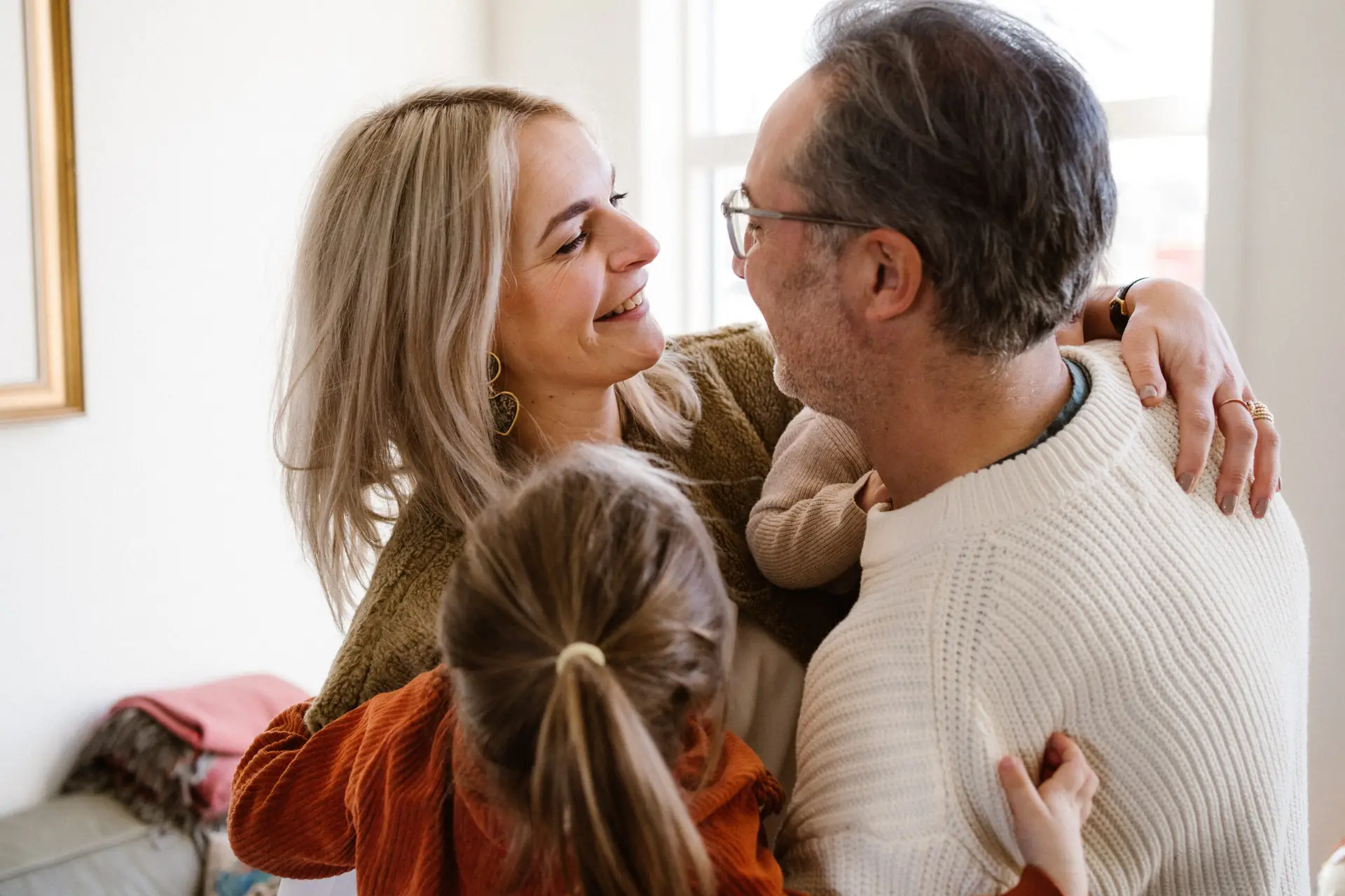 Ouders knuffelen elkaar, hun dochter kruipt ertussen